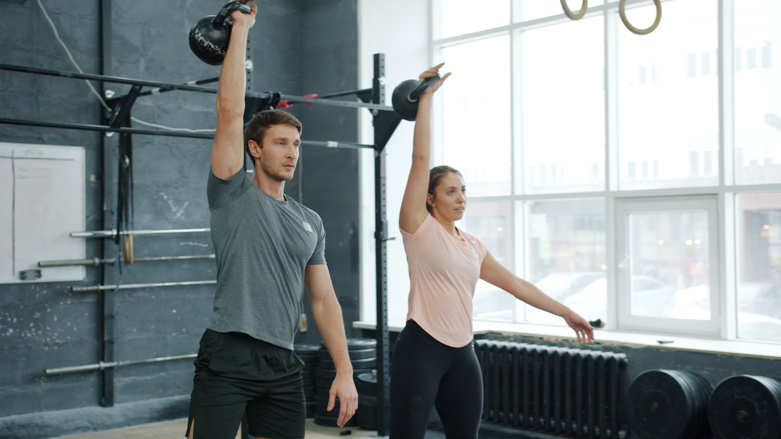 Dvaja športovci cvičia s kettlebellmi